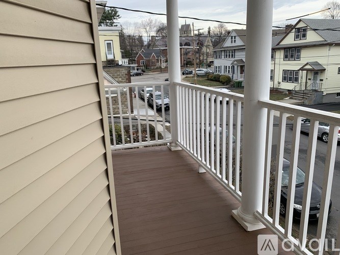 A balcony with a white railing and a brown floor.