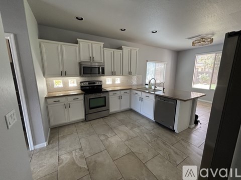 A kitchen with white cabinets and a tiled floor.