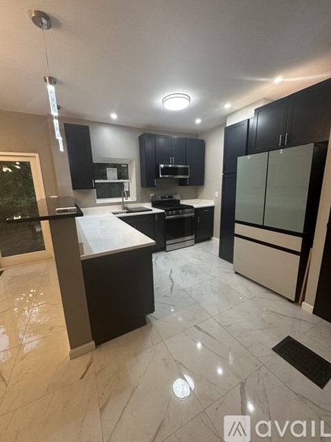 A modern kitchen with black cabinets and a marble floor.