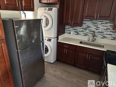 A black refrigerator stands in a kitchen next to a washing machine.