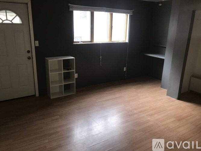 A room with a white door, a window with sunlight coming through, and a shelf with empty space.