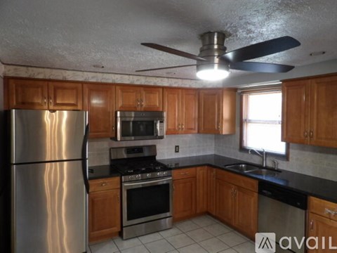 A kitchen with wooden cabinets and a stainless steel refrigerator.