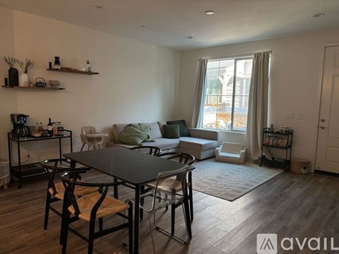 A living room with a black table and chairs, a white sofa, and a bookshelf with various items.