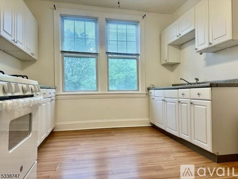 A kitchen with white cabinets and a wooden floor.