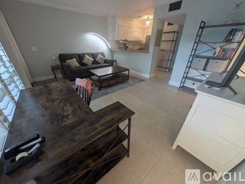 A living room with a dark wooden coffee table and a black couch with white pillows.