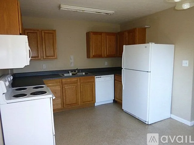 A kitchen with white appliances and wooden cabinets.