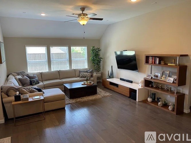 A living room with a large couch, a television, and a ceiling fan.
