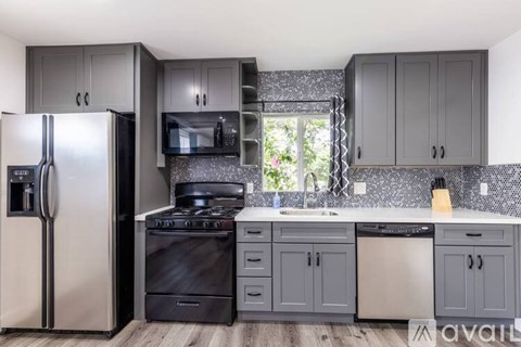 A kitchen with a black refrigerator and black appliances.