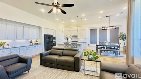 A modern living room with a black leather couch and a ceiling fan.