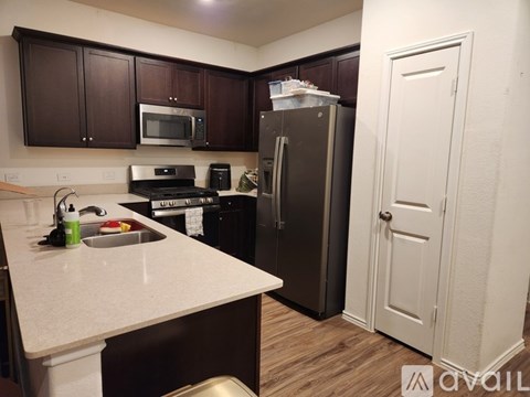 A kitchen with brown cabinets and a black fridge.