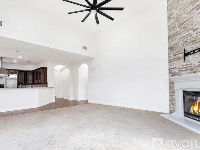 A spacious living room with a fireplace and a ceiling fan.