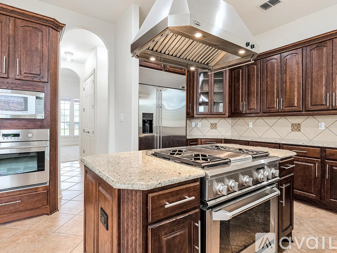 A kitchen with a stove top oven and wooden cabinets.