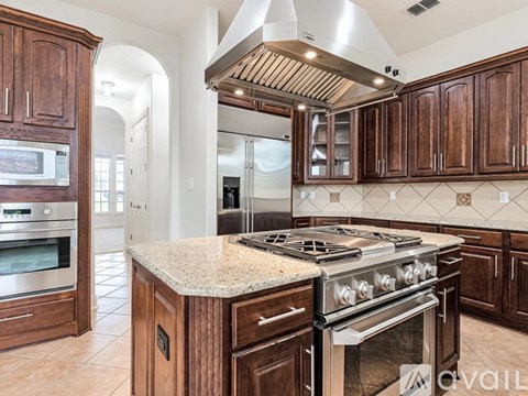 A kitchen with a stove top oven and wooden cabinets.