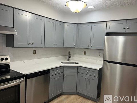 A kitchen with grey cabinets and a white countertop.