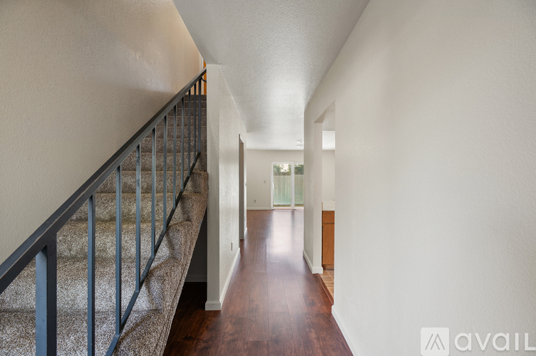 A long hallway with a staircase on the left and a door at the end.