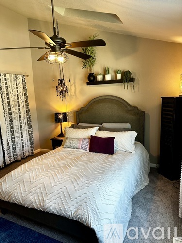 A bedroom with a large bed and a ceiling fan.