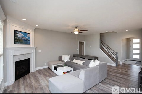 A living room with a grey couch, a fireplace, and a painting on the wall.