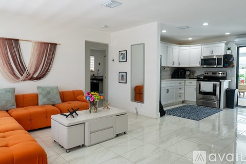 A modern living room with orange sofa and a kitchen in the background.