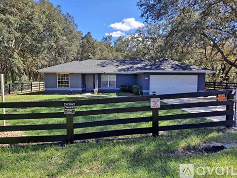 A house with a fence and a sign in front of it.