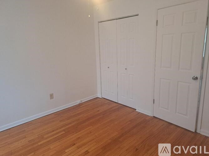 A room with a white door and a wooden floor.