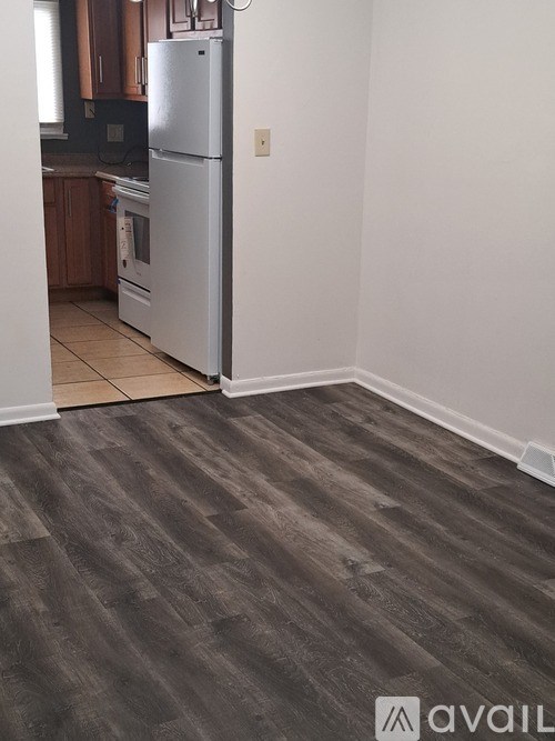 A kitchen with a refrigerator and a wooden floor.