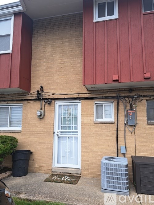 A red building with a white door and a doormat that says "hello".