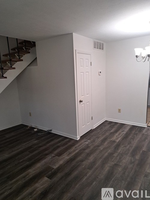 A room with a wooden staircase and a white door.