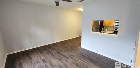 A room with a window and a kitchen visible through the window.