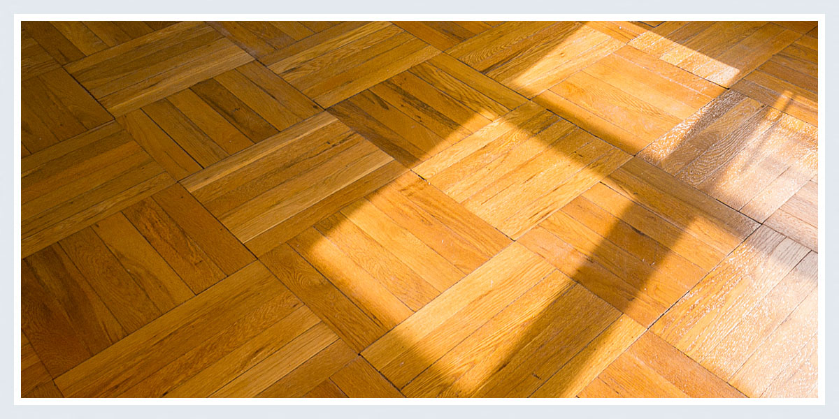 a wooden parquet floor with shadows on it