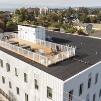A white building with a flat roof and a balcony.