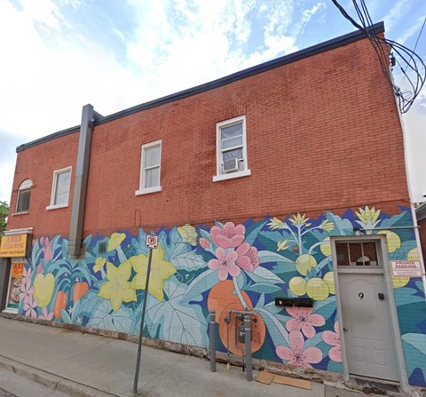 A red brick building with a mural of flowers painted on the side.