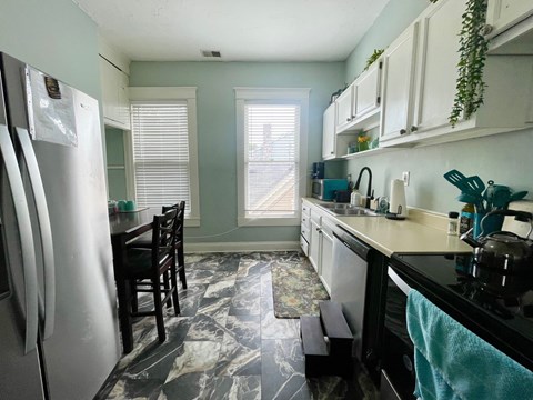 A kitchen with a marble floor and a black counter top.