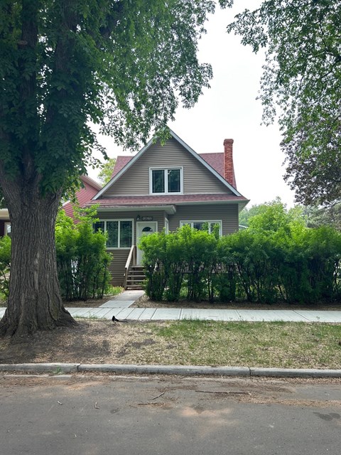 A house with a red roof and a tree in front of it.