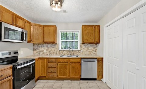 A kitchen with wooden cabinets and a stainless steel dishwasher.