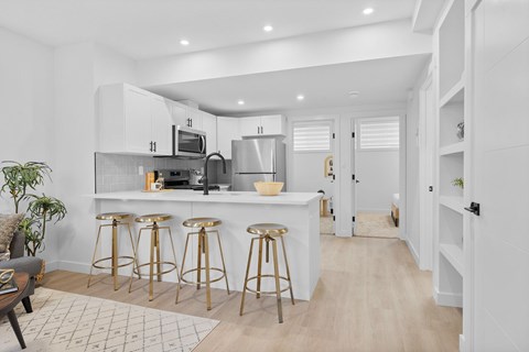 A kitchen with white cabinets and a white countertop with a microwave and oven.
