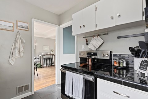 A kitchen with a black stove top and white cabinets.