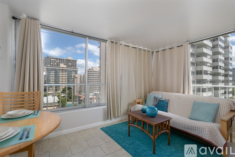 A living room with a couch, table, and a window overlooking a cityscape.