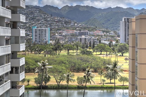 A view of a cityscape with buildings, trees, and mountains in the background.