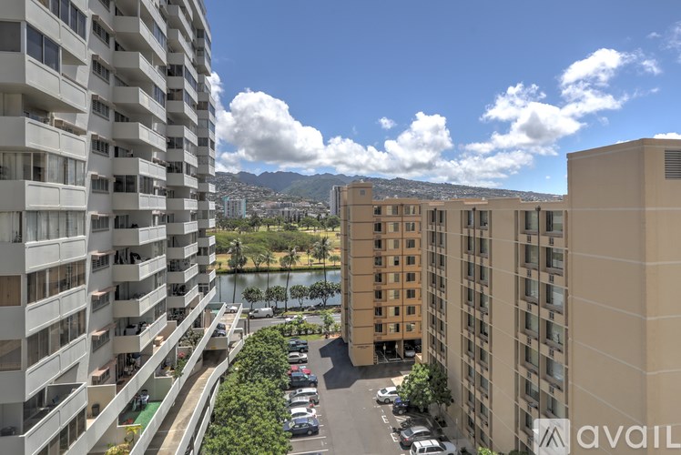 A view of a residential area with apartment buildings, a parking lot, and a body of water in the distance.