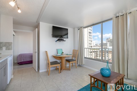 A living room with a television, a dining table with chairs, and a view of the city.