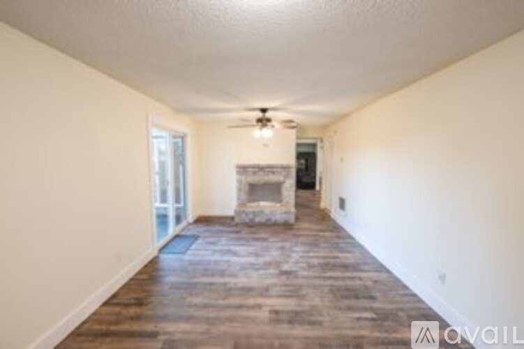A spacious room with a fireplace and a ceiling fan.