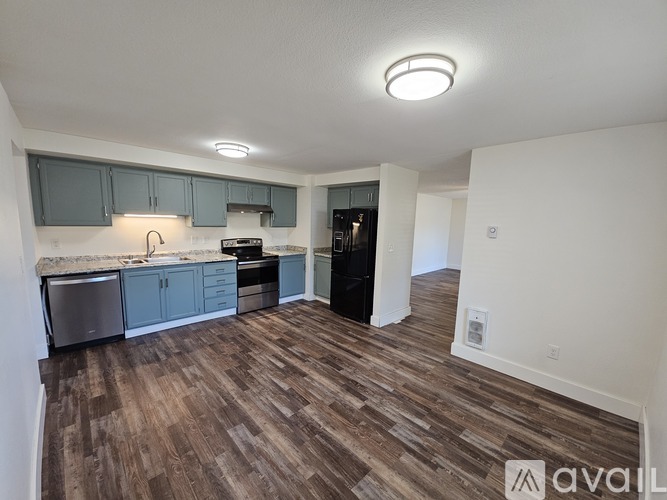 A black refrigerator in a kitchen with wooden floors.
