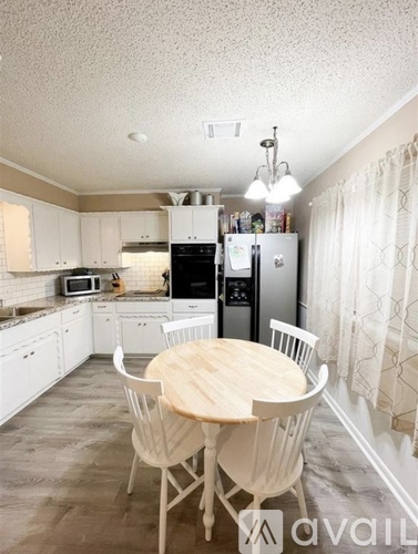 A kitchen with a table and chairs in front of it.
