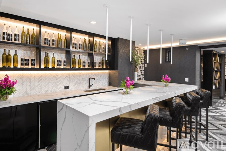 A modern kitchen with a marble countertop and black chairs.