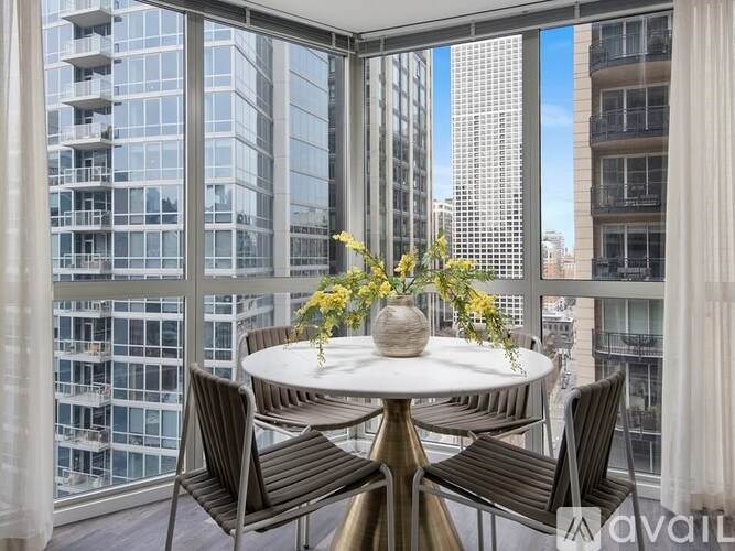 A table with chairs and flowers on a balcony with a view of buildings.