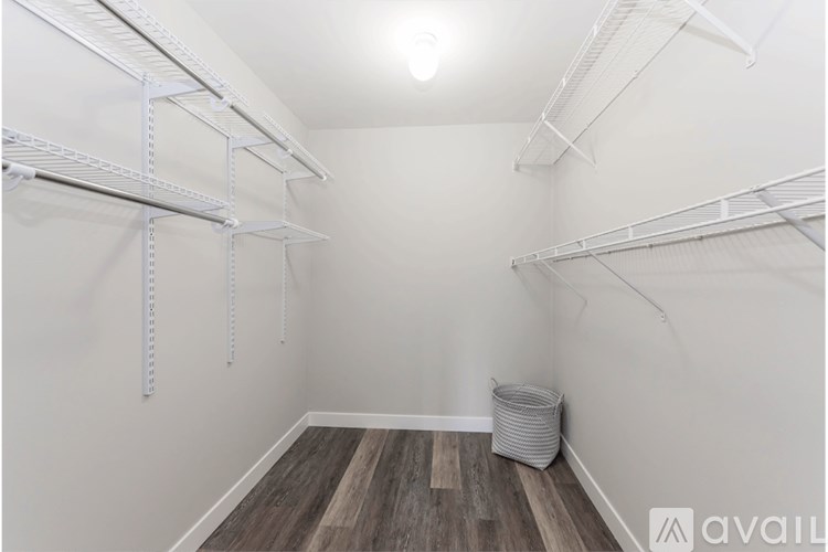 A room with white walls and wooden flooring, equipped with metal shelving.