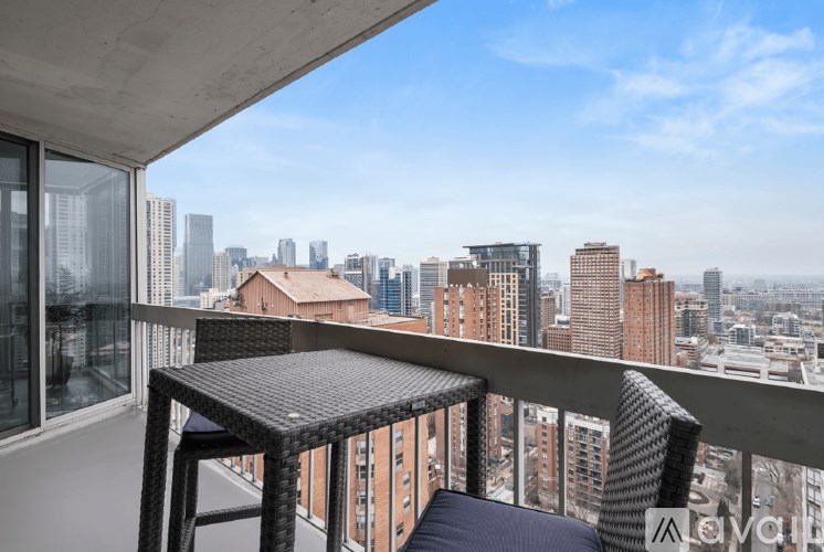 A balcony with a table and two chairs overlooking a cityscape.