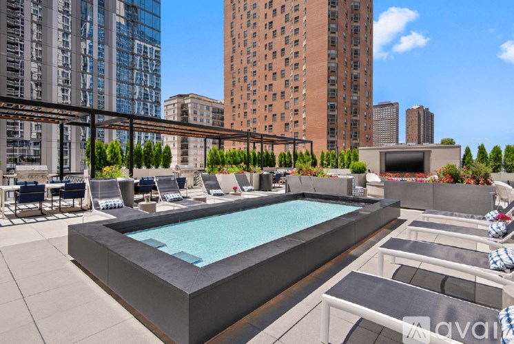 A rooftop pool with lounge chairs and a city skyline in the background.