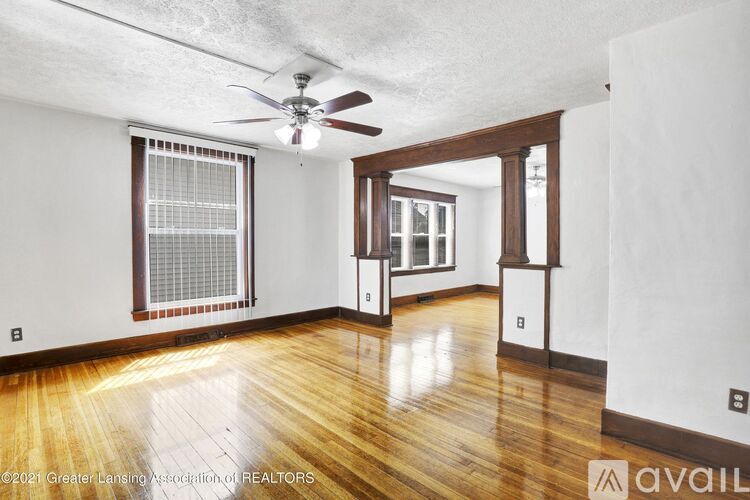 A room with a ceiling fan and wooden flooring.