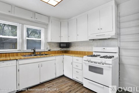 A kitchen with white cabinets and a white stove top oven.